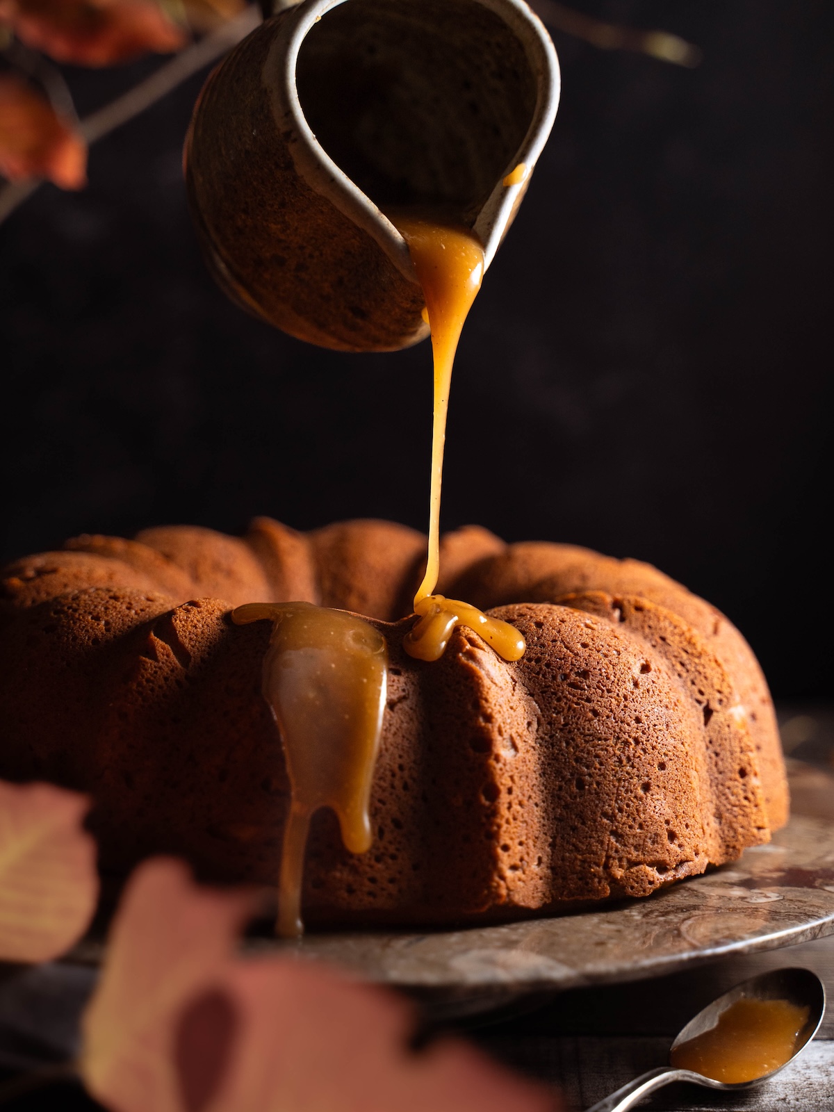Drizzling homemade toffee sauce onto a bundt cake