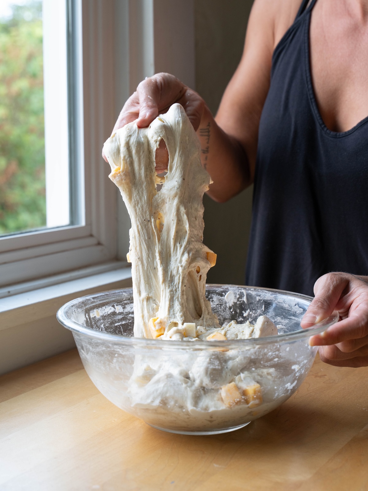 Stretching cheesy sourdough bread dough to build gluten
