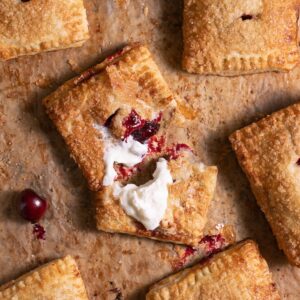 Freshly baked cherry hand pies, with one pie broken open to show filling