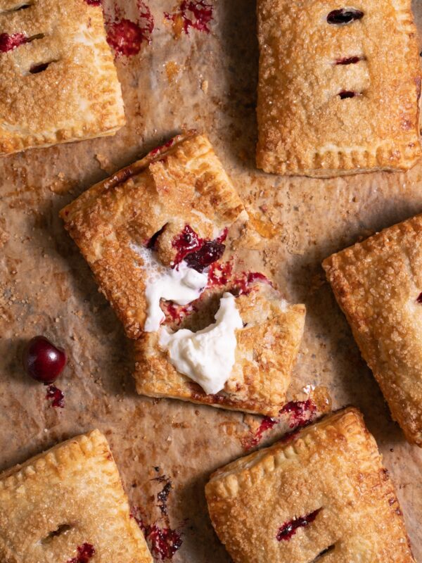 Freshly baked cherry hand pies, with one pie broken open to show filling