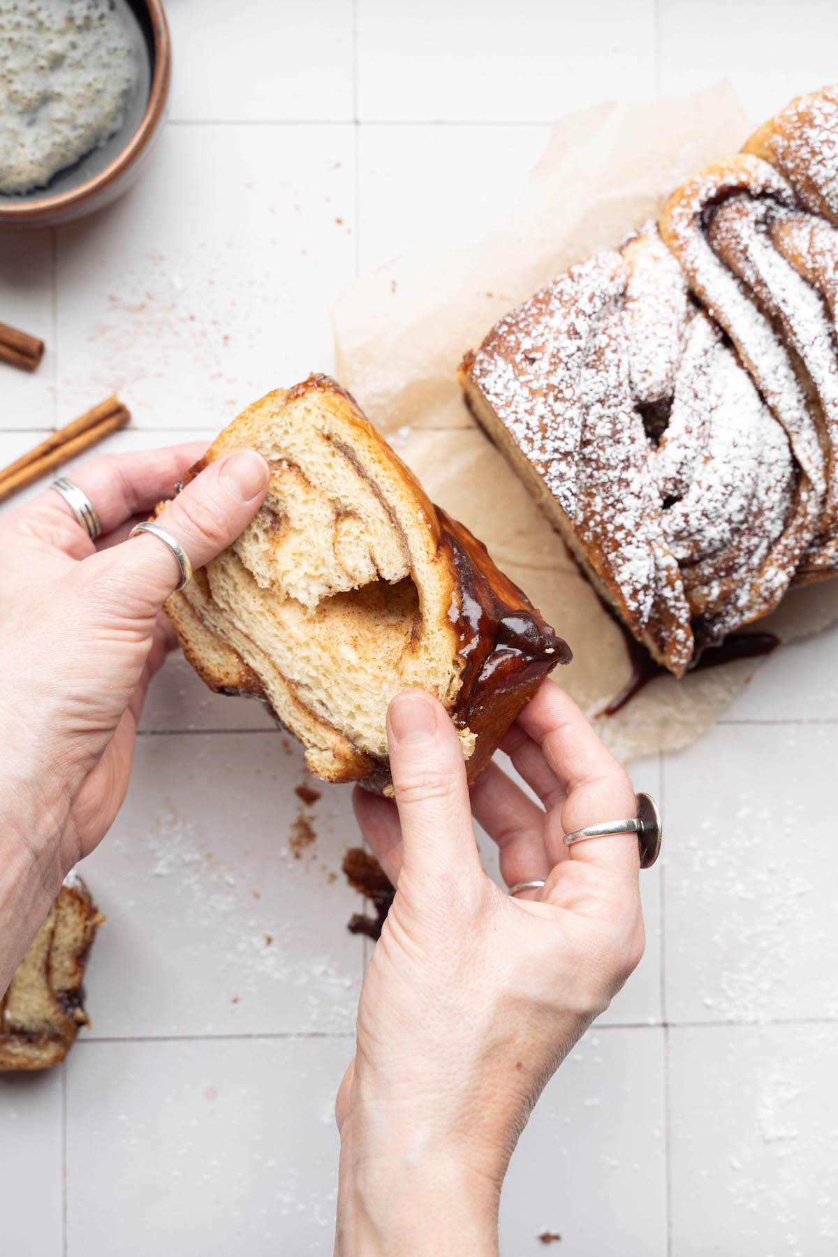 Hands showing the gooey underside of cinnamon swirl bread