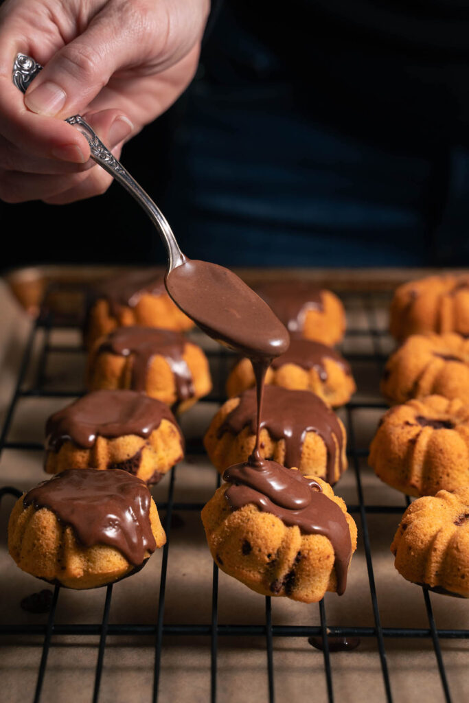 Drizzling ganache onto pumpkin chocolate cakes