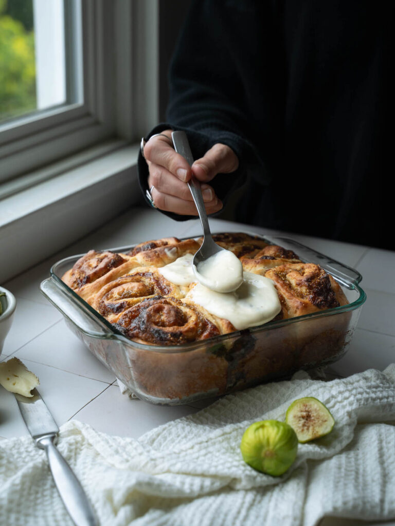 Topping fig cinnamon rolls with honey cream cheese frosting
