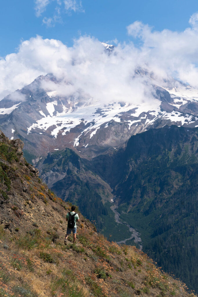 Man on a hiking trail in front of a snow-capped mountain