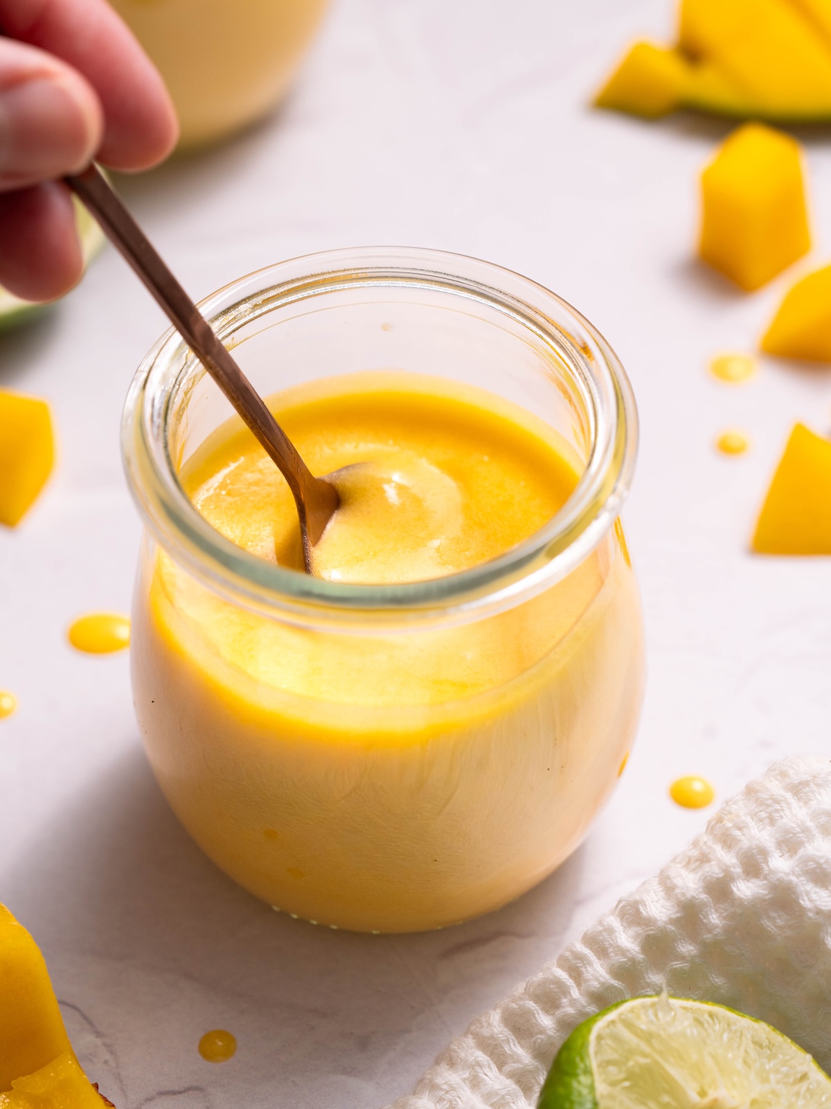 Dipping a copper spoon into a jar of fresh mango curd