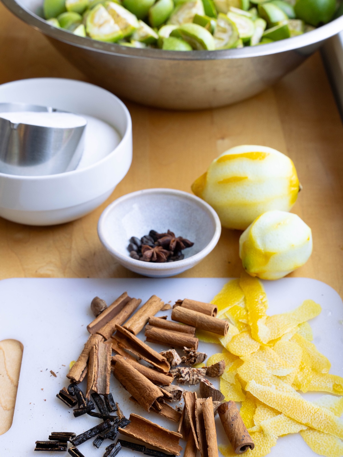 Ingredients needed for Nocino - lemon peel, whole spices, sugar, and green walnuts