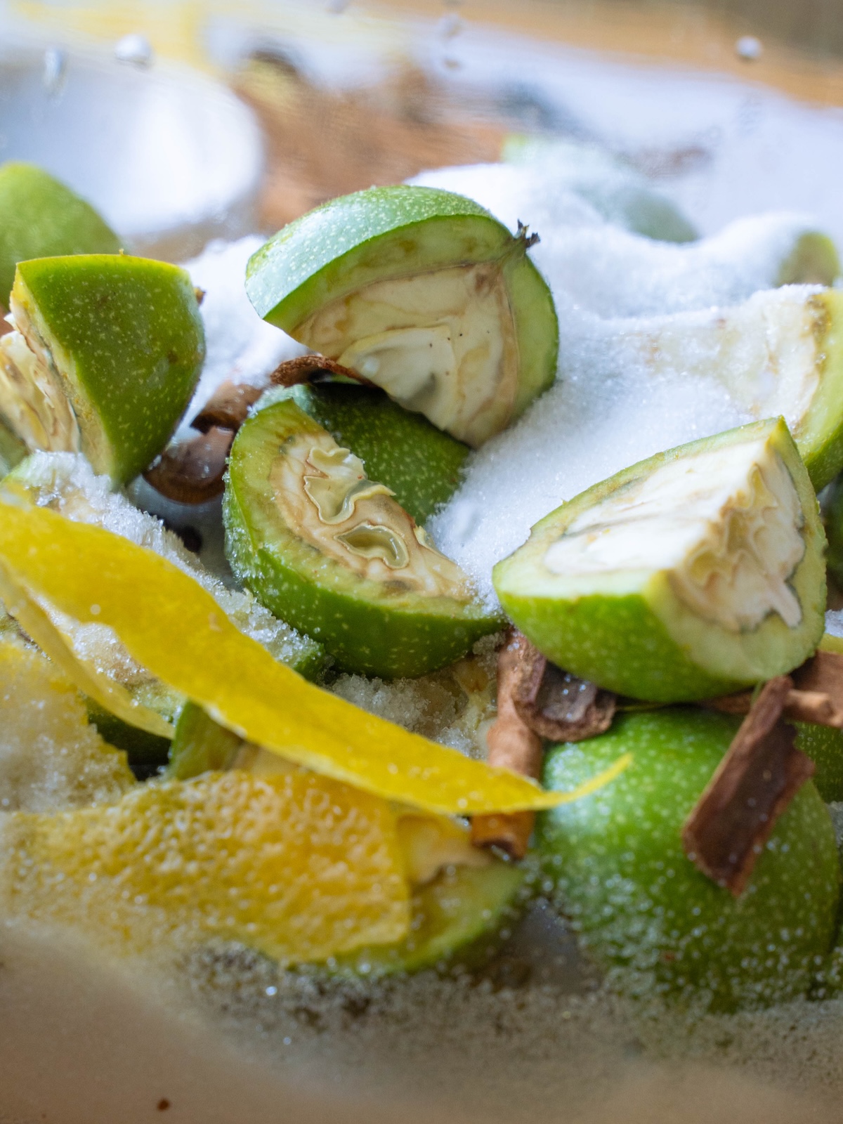 Unripe walnuts, lemon peel, spices, and sugar layered in a jar