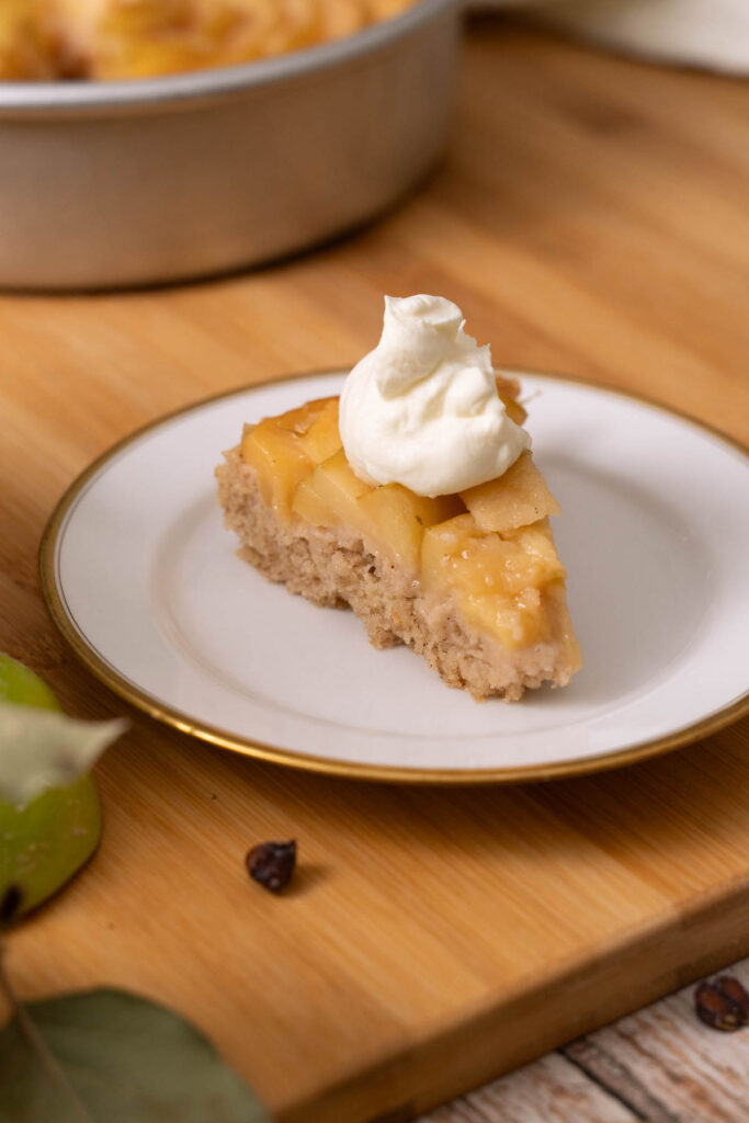 A slice of quince  spice cake topped with whipped cream