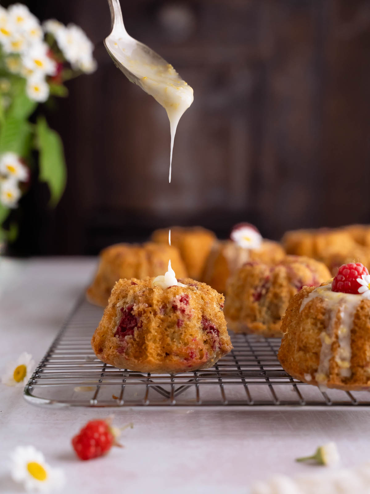 Lemon glaze dripping off a spoon onto a mini bundt cake