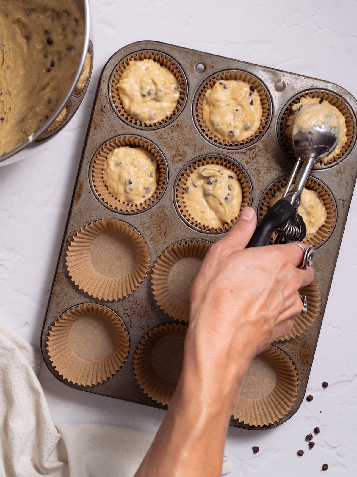 Scooping muffin batter into a lined muffin pan