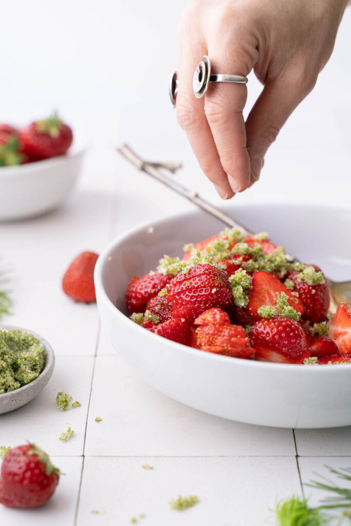 Sprinkling strawberries with fir tip sugar
