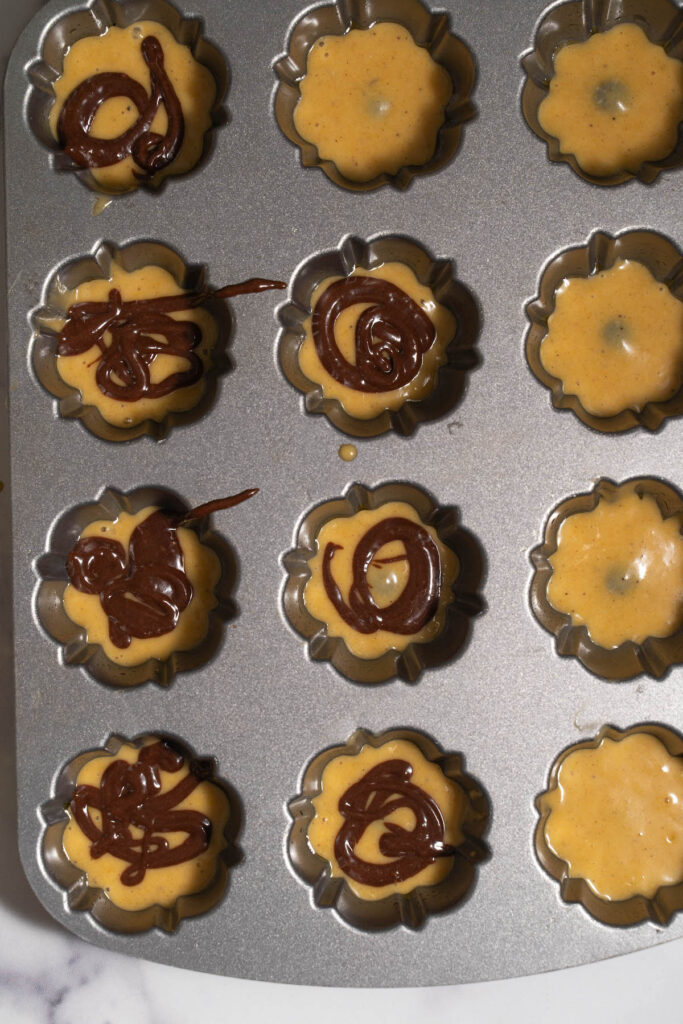 Swirling chocolate and pumpkin cake batter in mini bundt pan