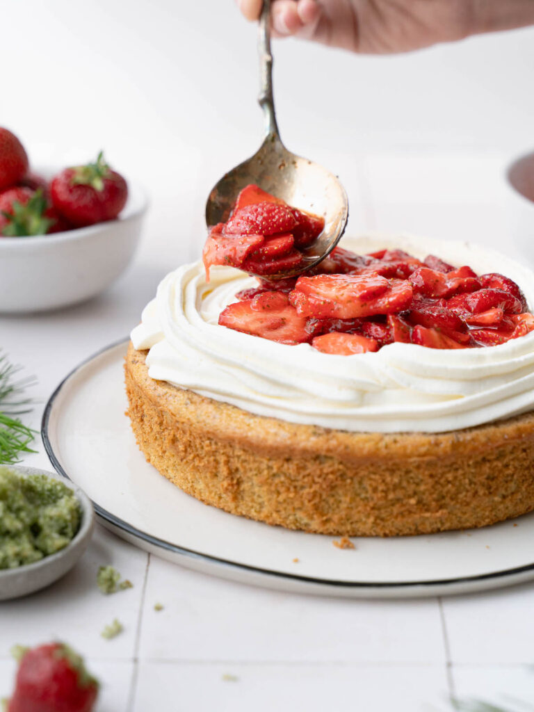 Spooning strawberries on top of a cake