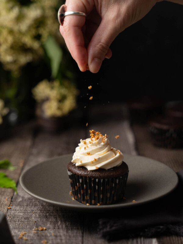 Decorating an elderflower cupcake with candied elderflowers