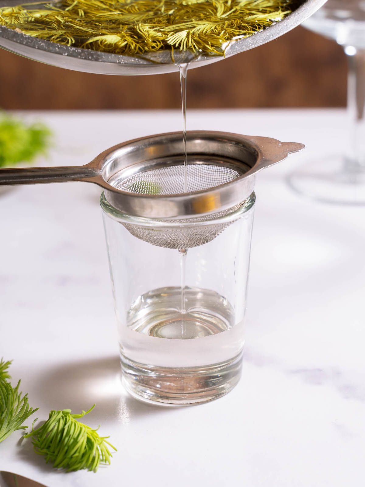 Straining fir tip syrup into a glass