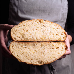 A loaf of roasted garlic parmesan sourdough split in half to show interior