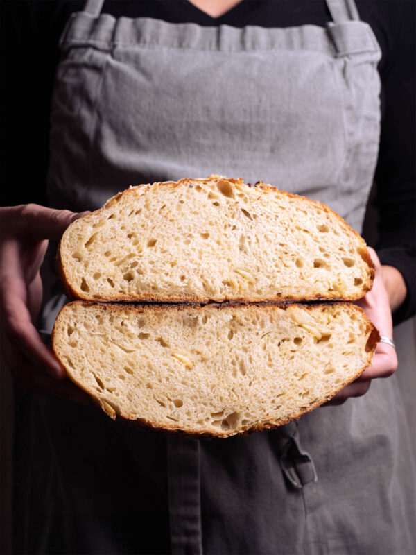 A loaf of roasted garlic parmesan sourdough split in half to show interior