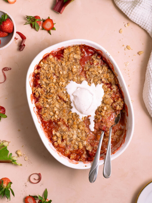 Strawberry rhubarb crisp with whipped cream melting on top