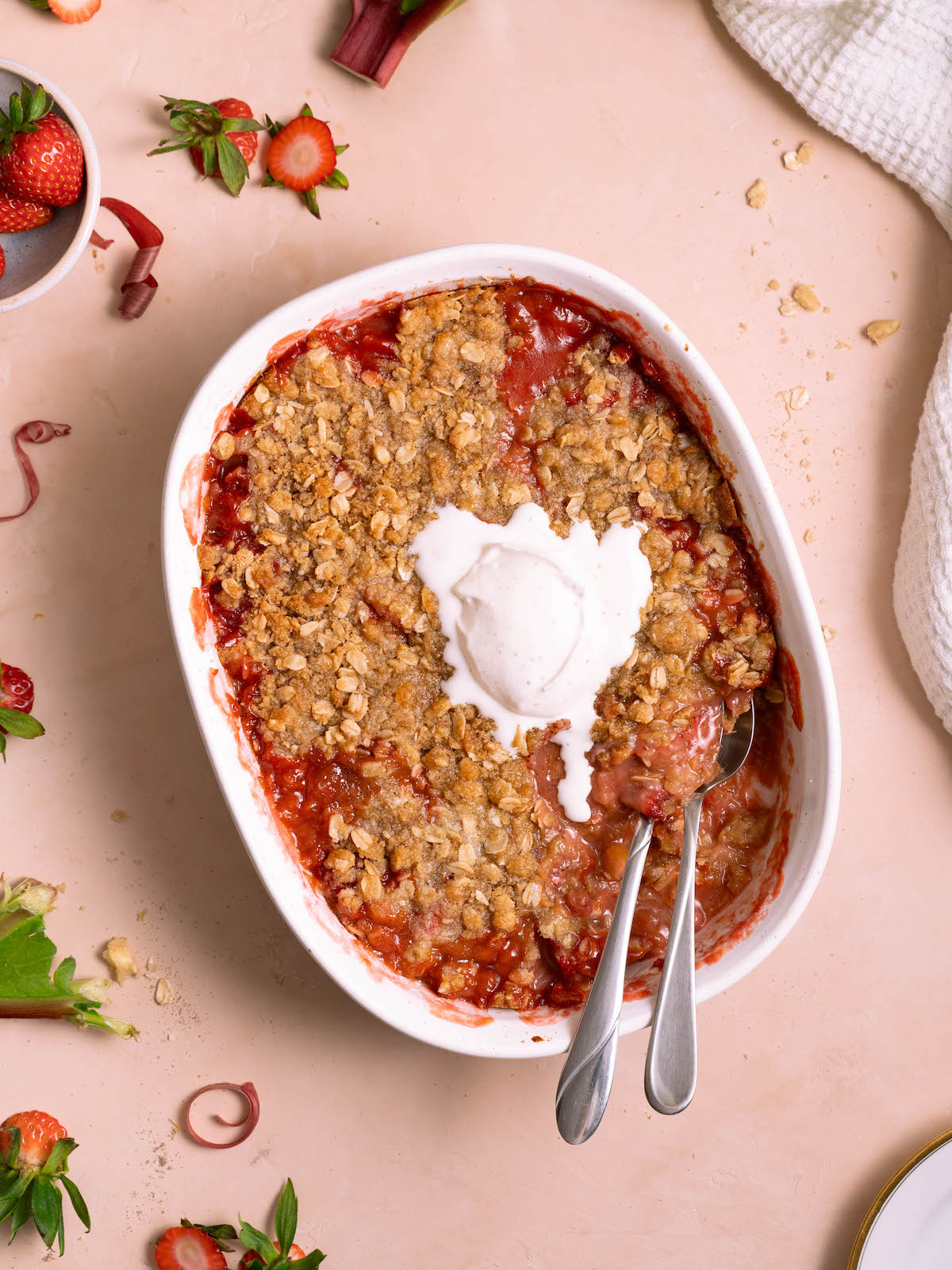 Strawberry rhubarb crisp with whipped cream melting on top
