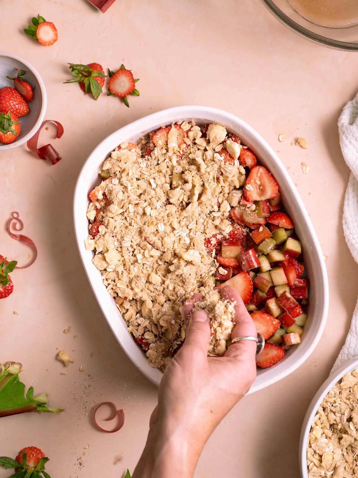 Sprinkling crisp topping over strawberry rhubarb filling