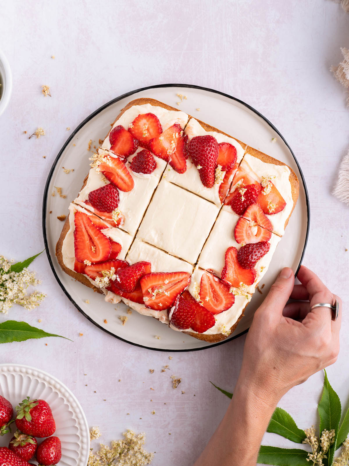 A square cake with strawberries on top, sliced into 9 pieces