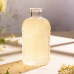 A jar of elderflower syrup sitting in the window light on a summer afternoon