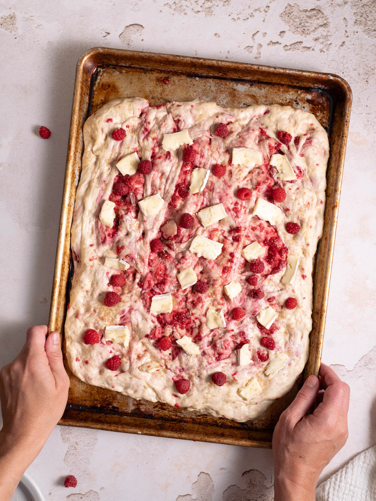 Homemade focaccia dough topped with raspberries and brie cheese
