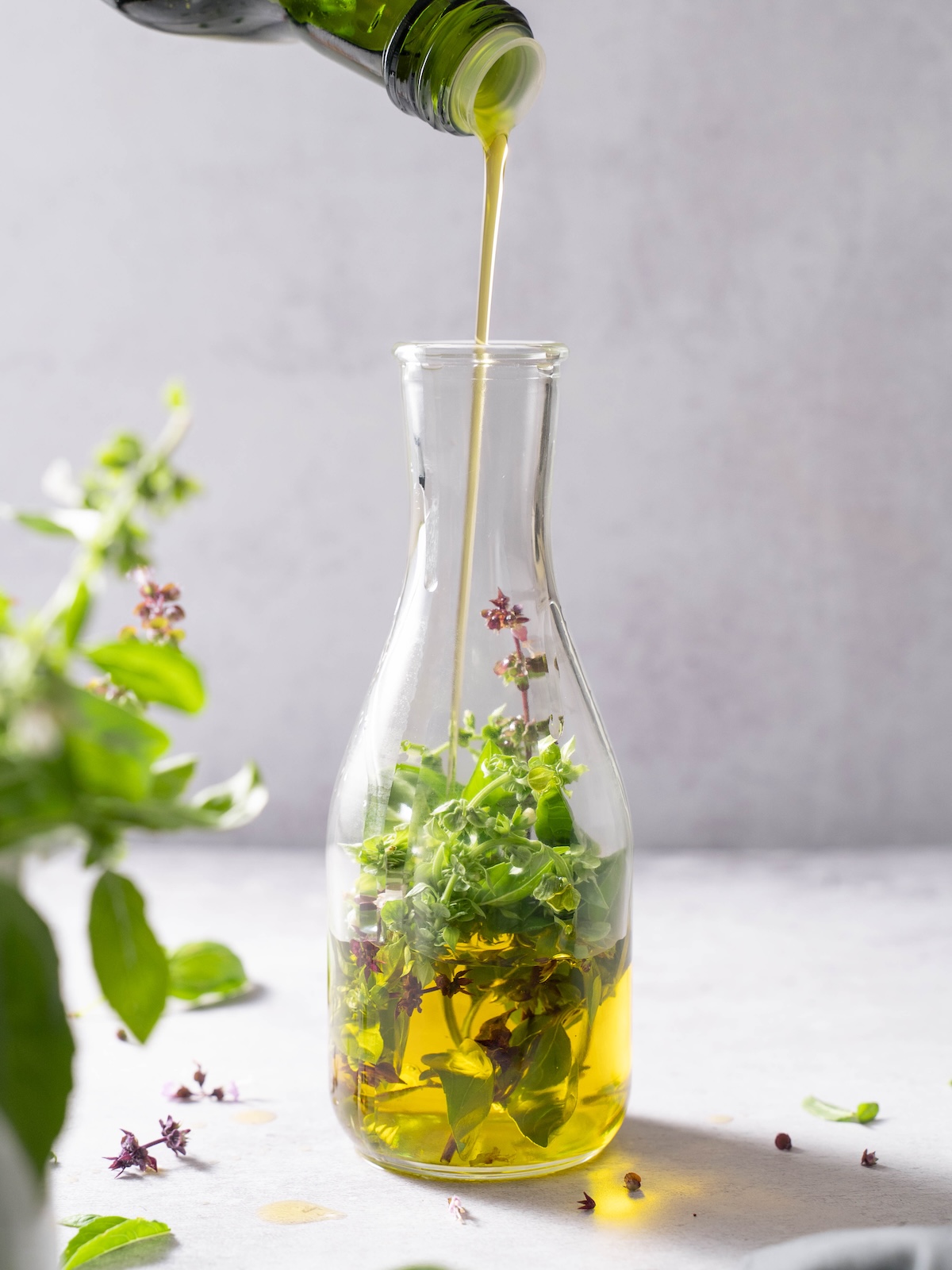 Pouring oil over flowering basil tops in a jar