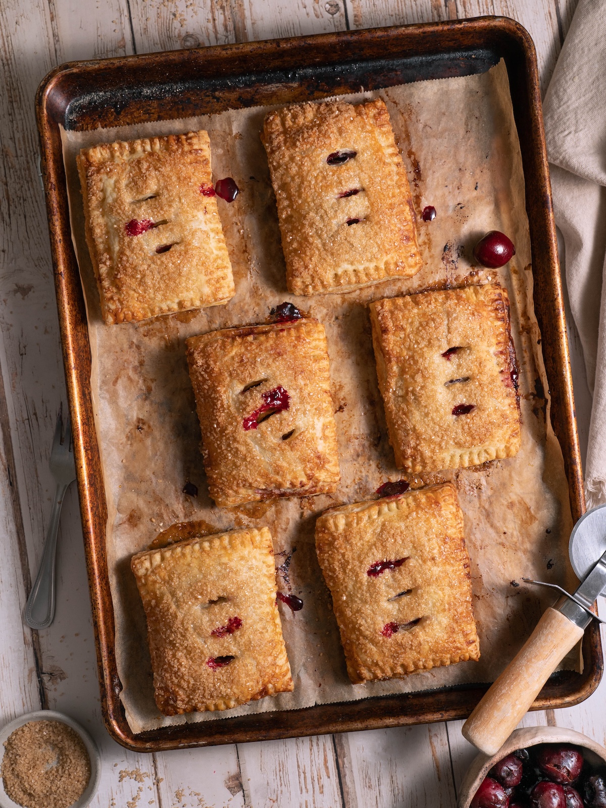 A baking sheet with freshly baked cherry puff pastry pies