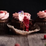 Raspberry chocolate cupcakes broken open to show raspberry jam filling inside