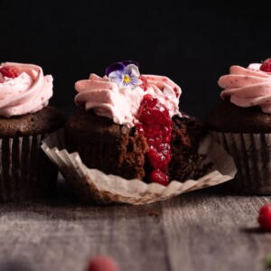 Raspberry chocolate cupcakes broken open to show raspberry jam filling inside