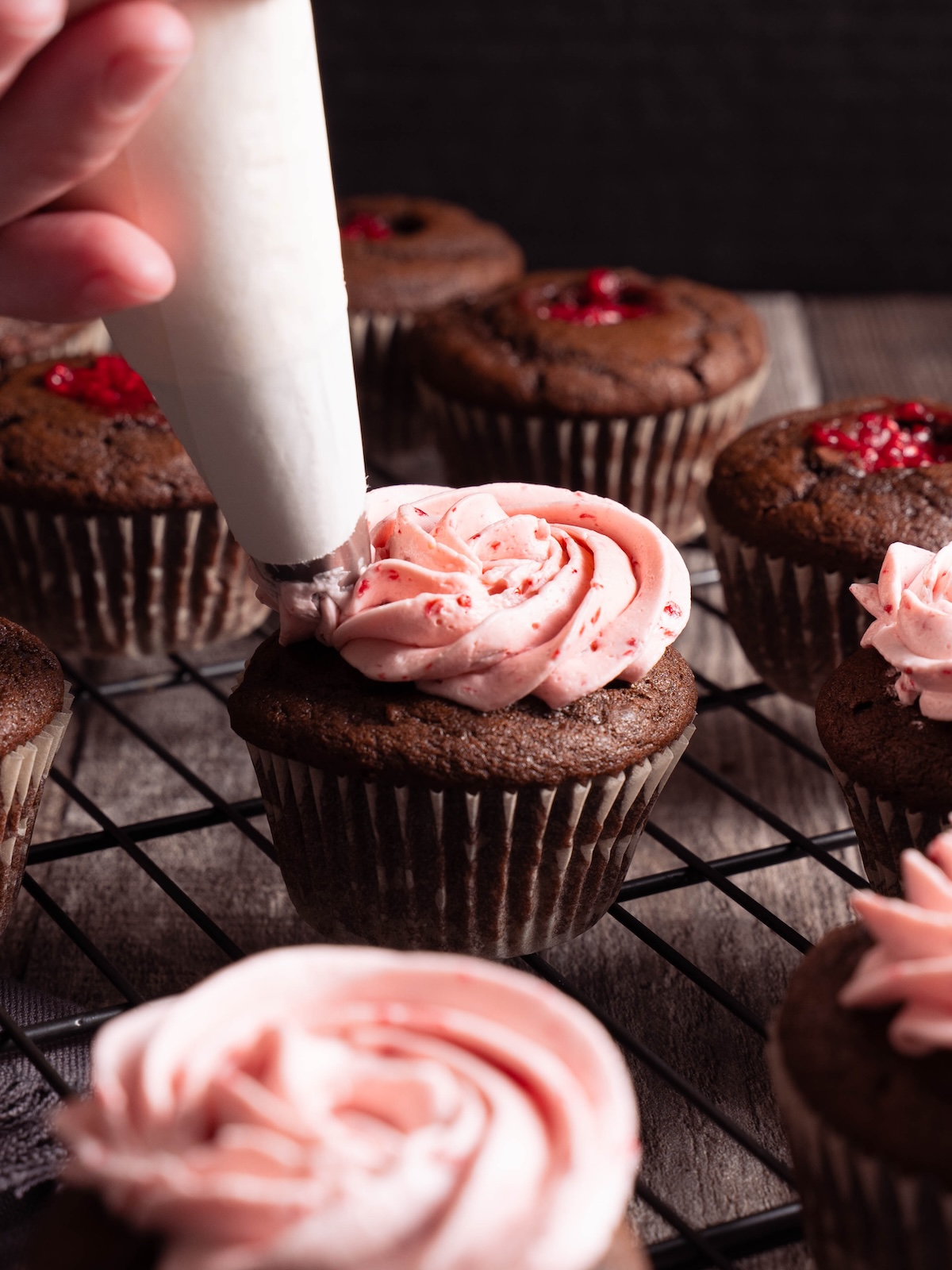 Piping raspberry buttercream on a chocolate cupake