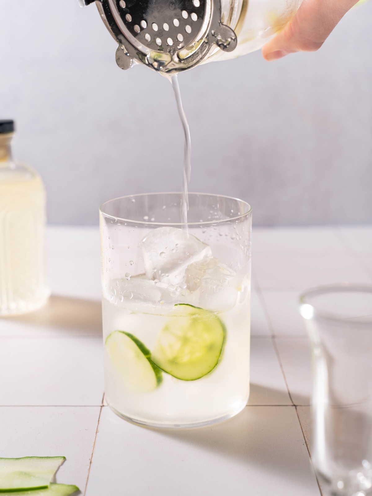Straining a White Linen cocktail into a glass filled with ice