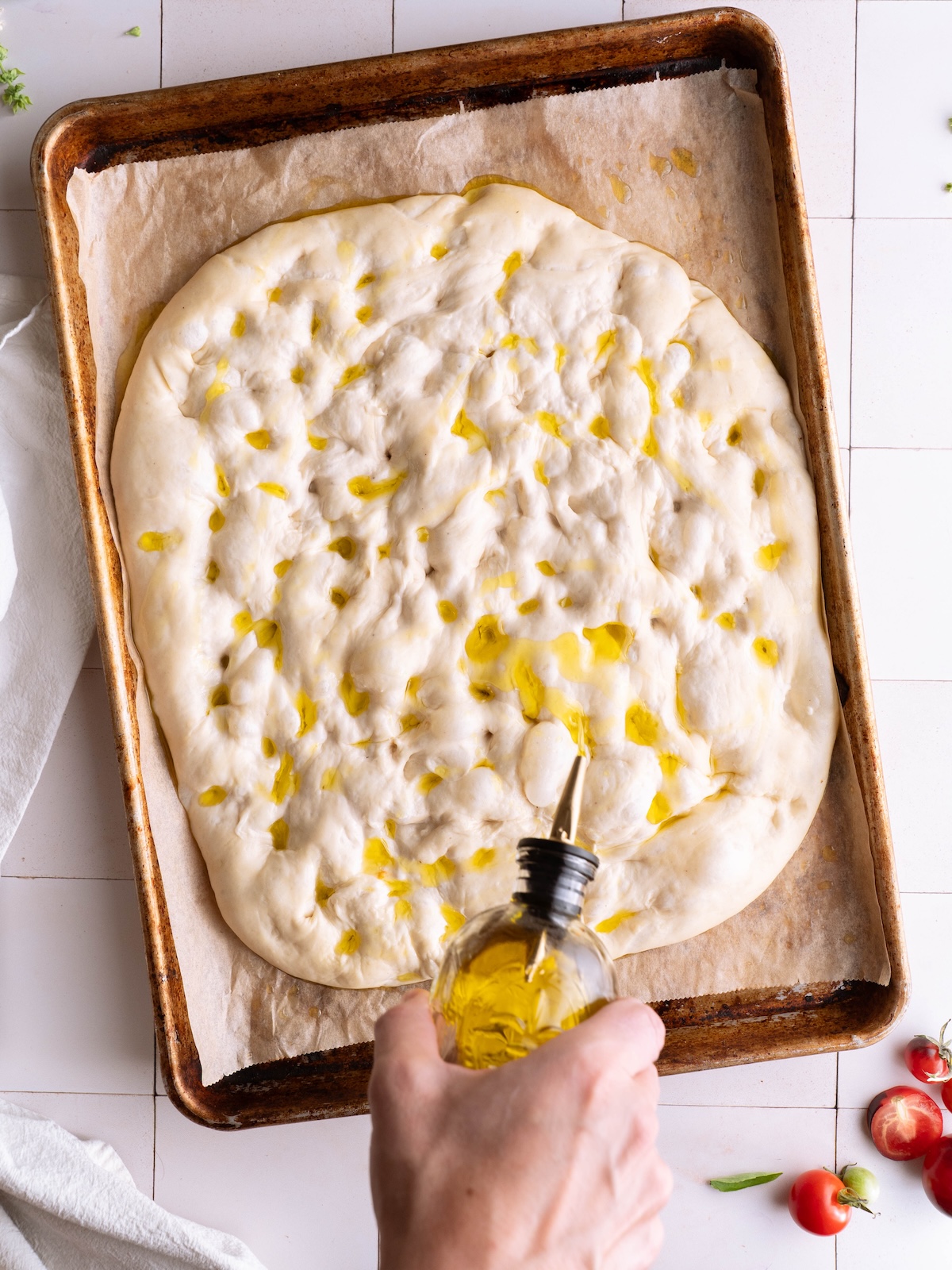 Drizzling basil flower oil onto sourdough focaccia before baking