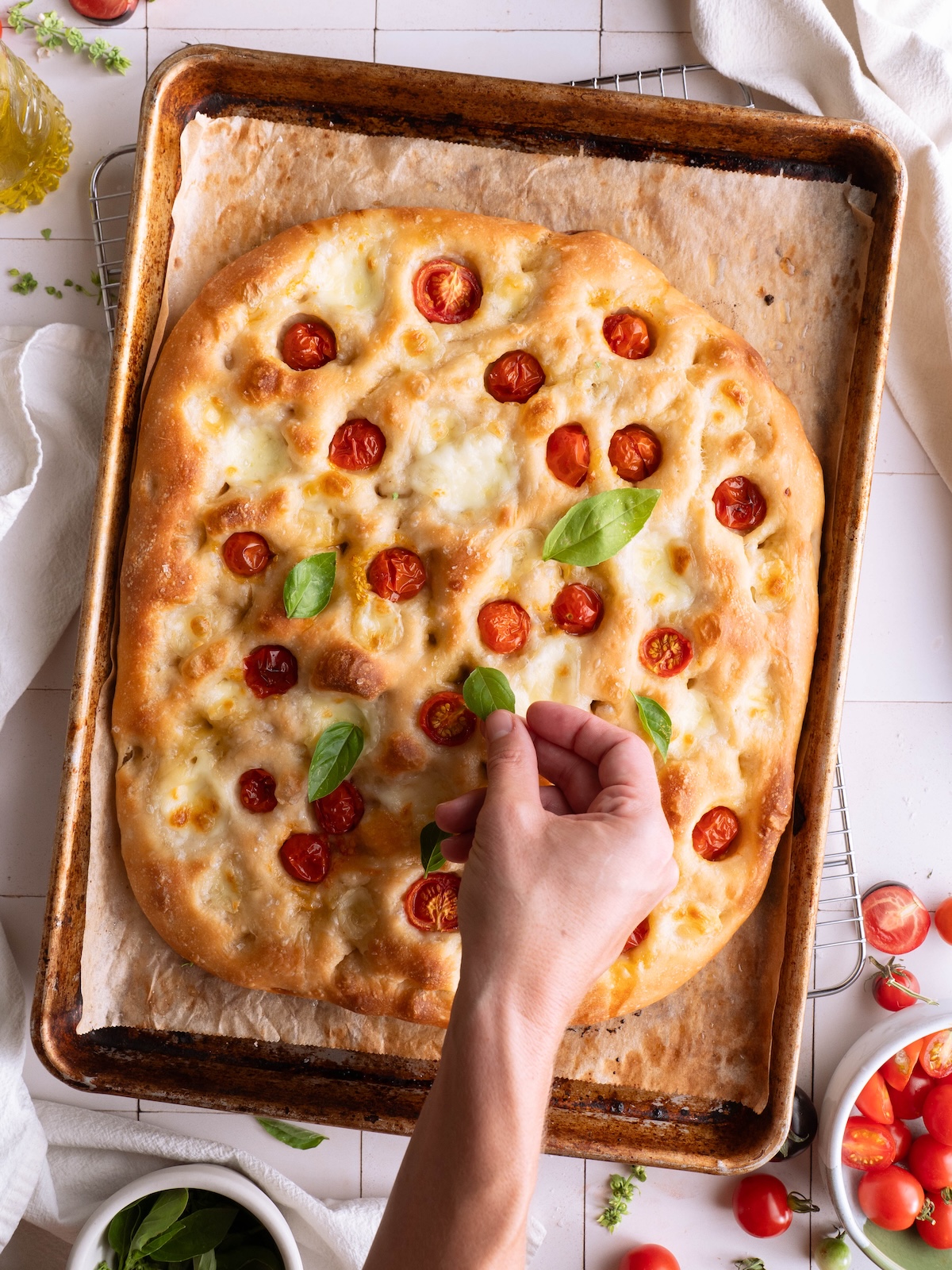 Topping fresh focaccia bread with basil leaves