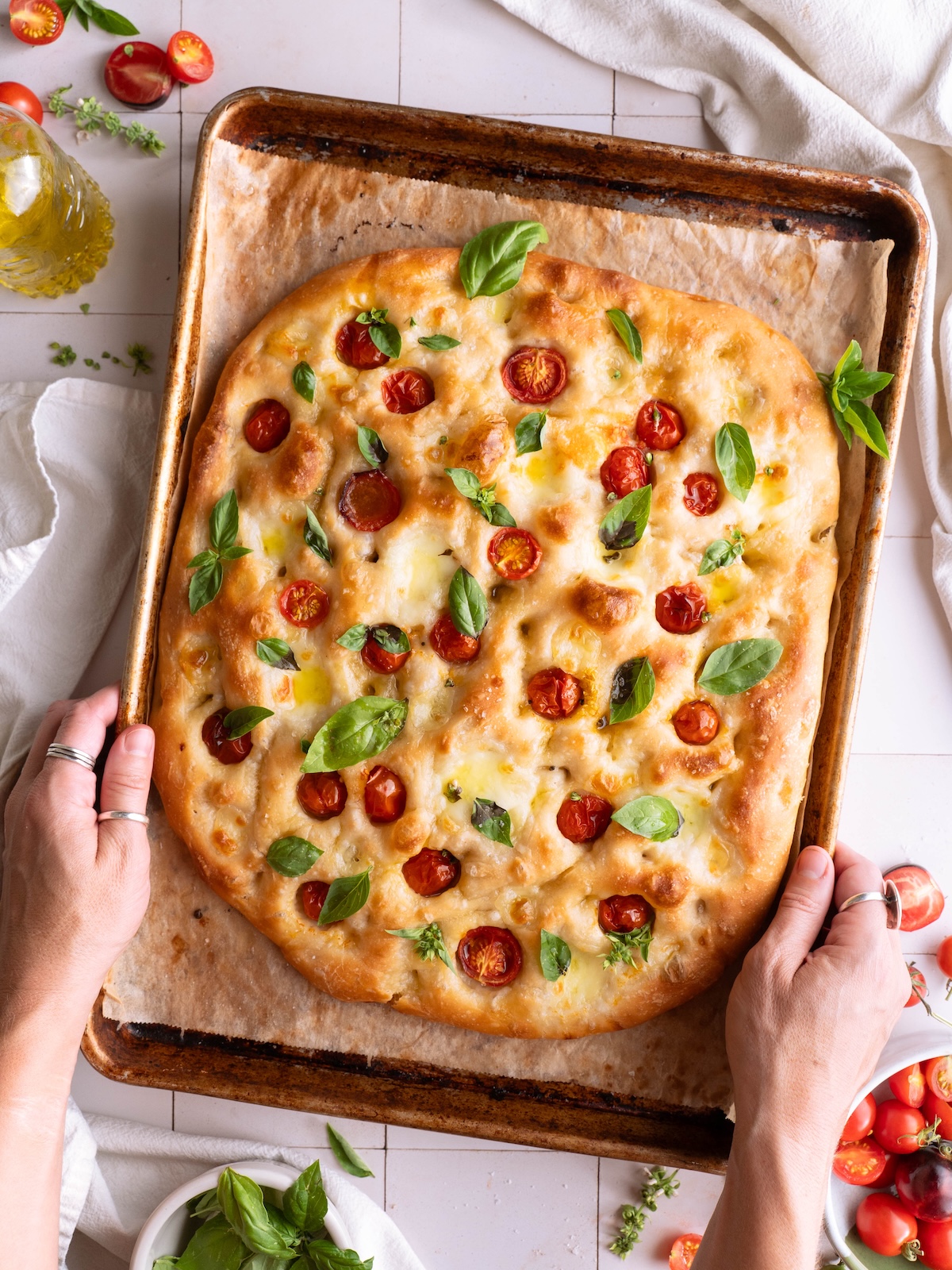 Hands holding a stunning loaf of homemade Caprese focaccia bread