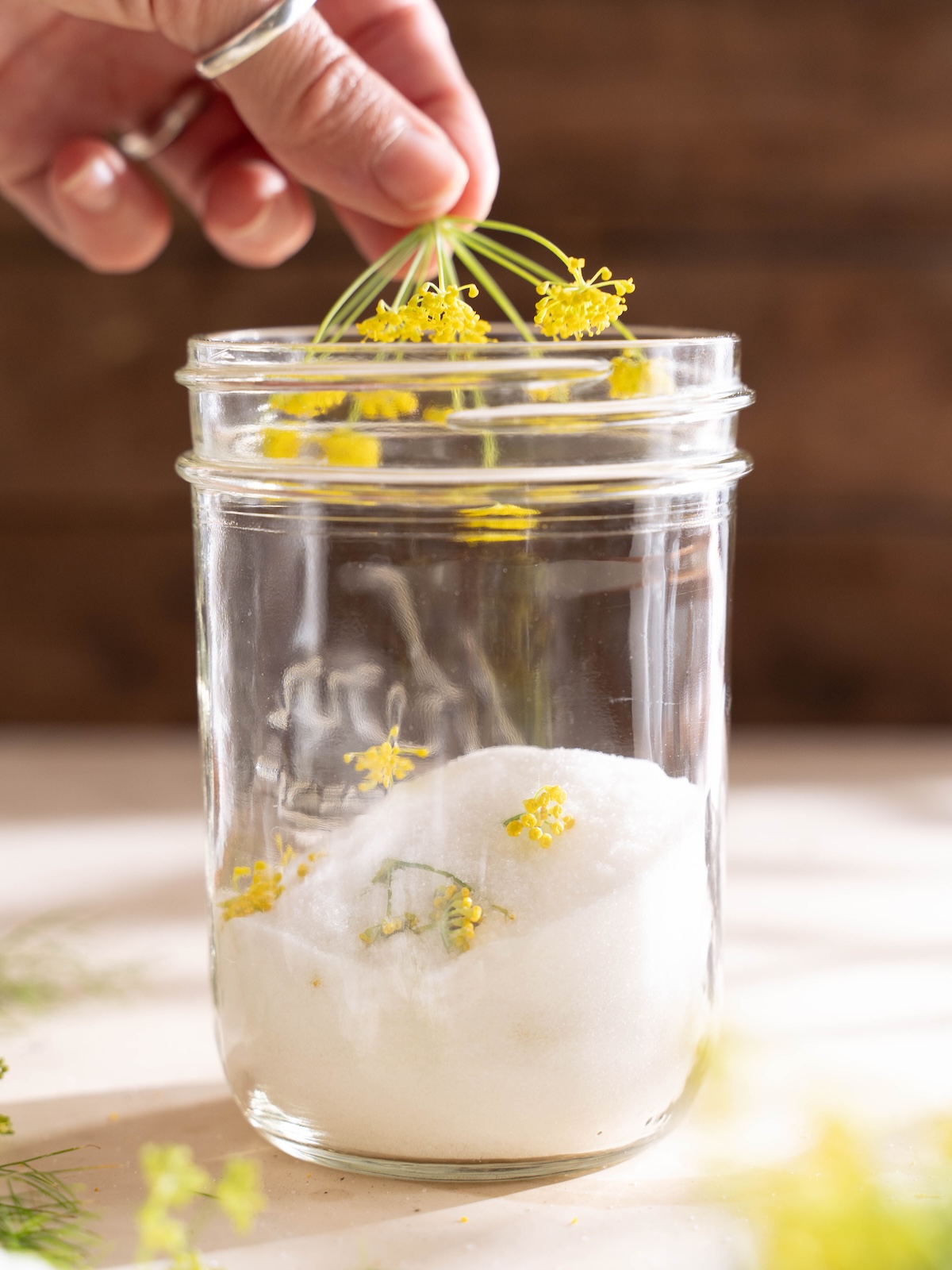 Placing fennel flowers in a jar of sugar