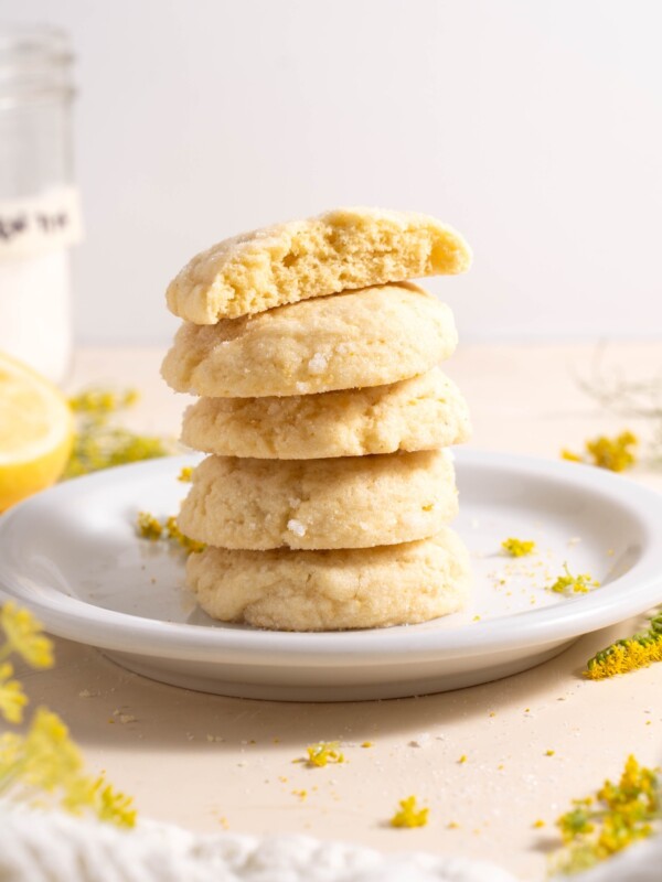 A stack of lemon and fennel pollen sugar cookies, surrounded by fennel flowers