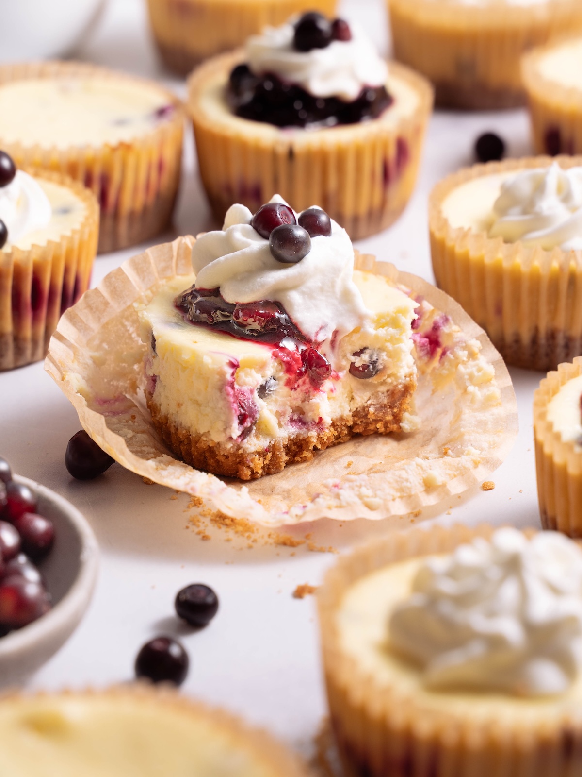 A bite taken out of a mini cheesecake filled with huckleberries