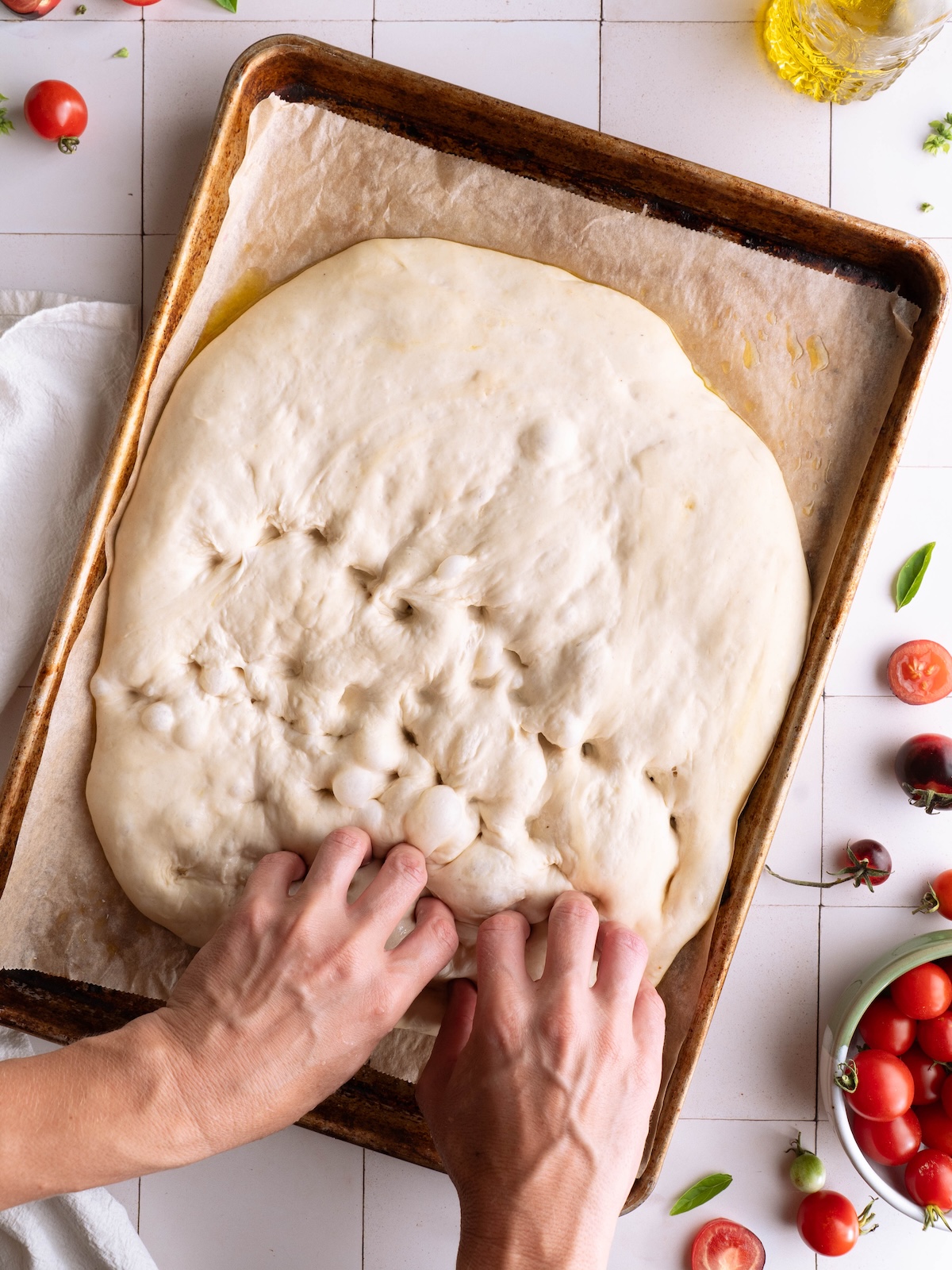 Hands dimpling homemade focaccia dough