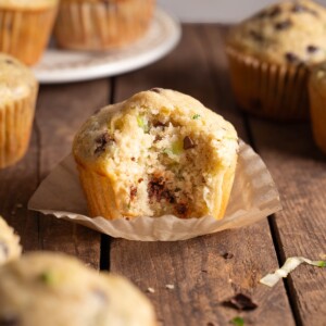 A sourdough zucchini chocolate chip muffin with a bite taken out of it