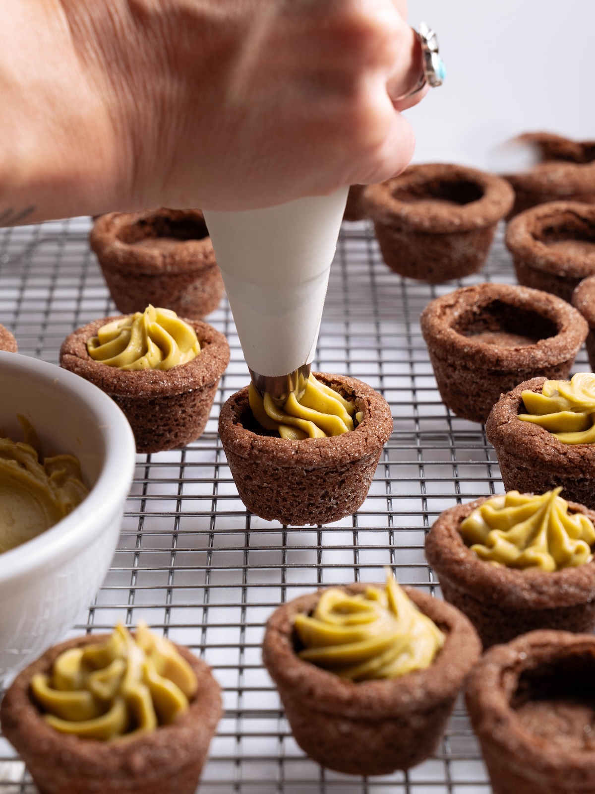 Filling a chocolate cookie cup with pistachio frosting