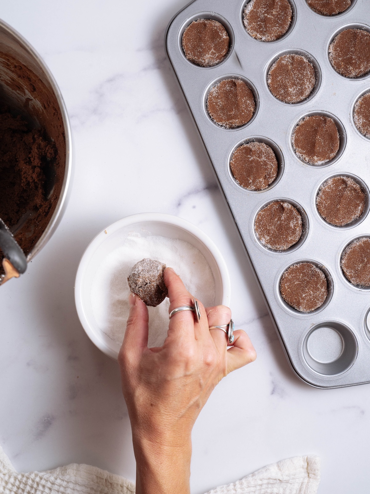 Rolling chocolate cookies in sugar before baking