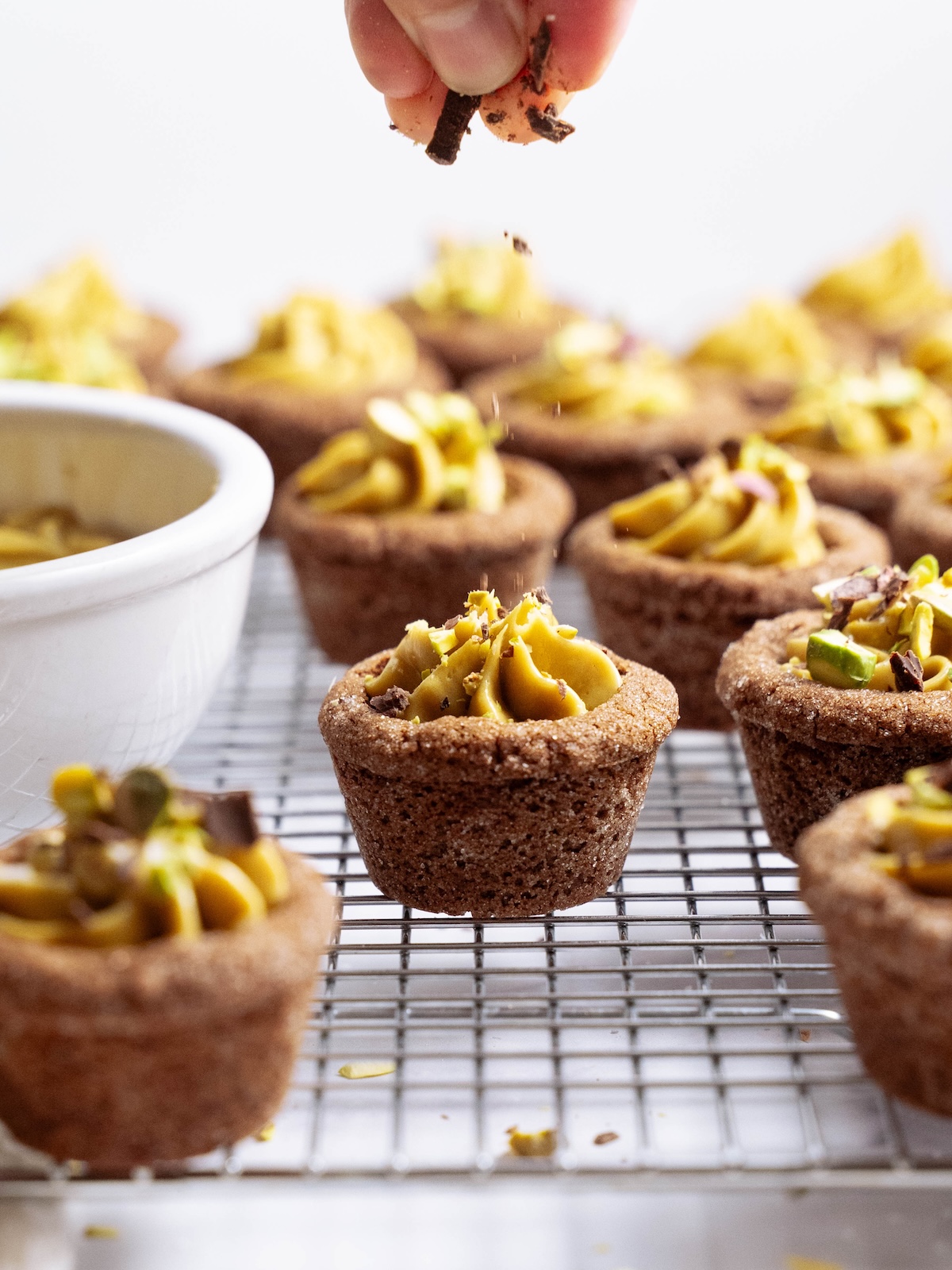 Sprinkling chopped chocolate onto cookie cups