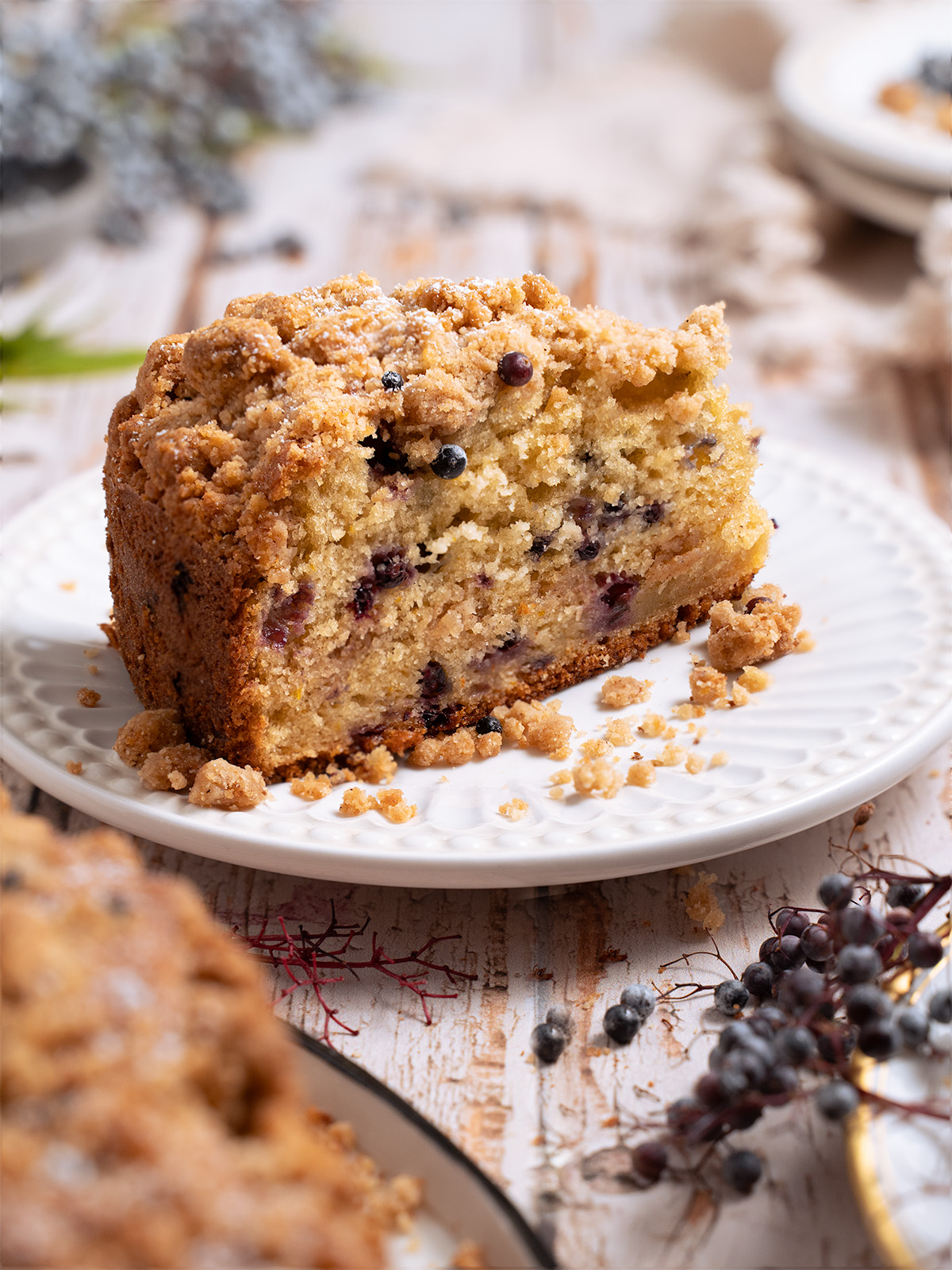A slice of coffee cake filled with wild berries, served on a white plate