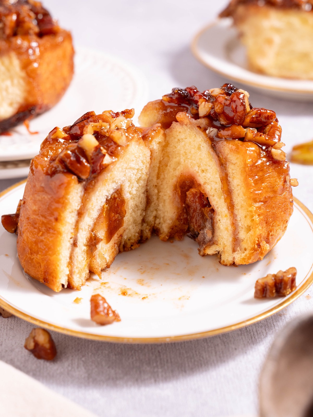A plum pecan sticky bun sliced in half to show the swirl inside