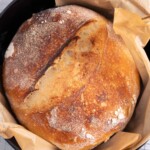 A freshly baked loaf of sourdough bread in a cast iron dutch oven