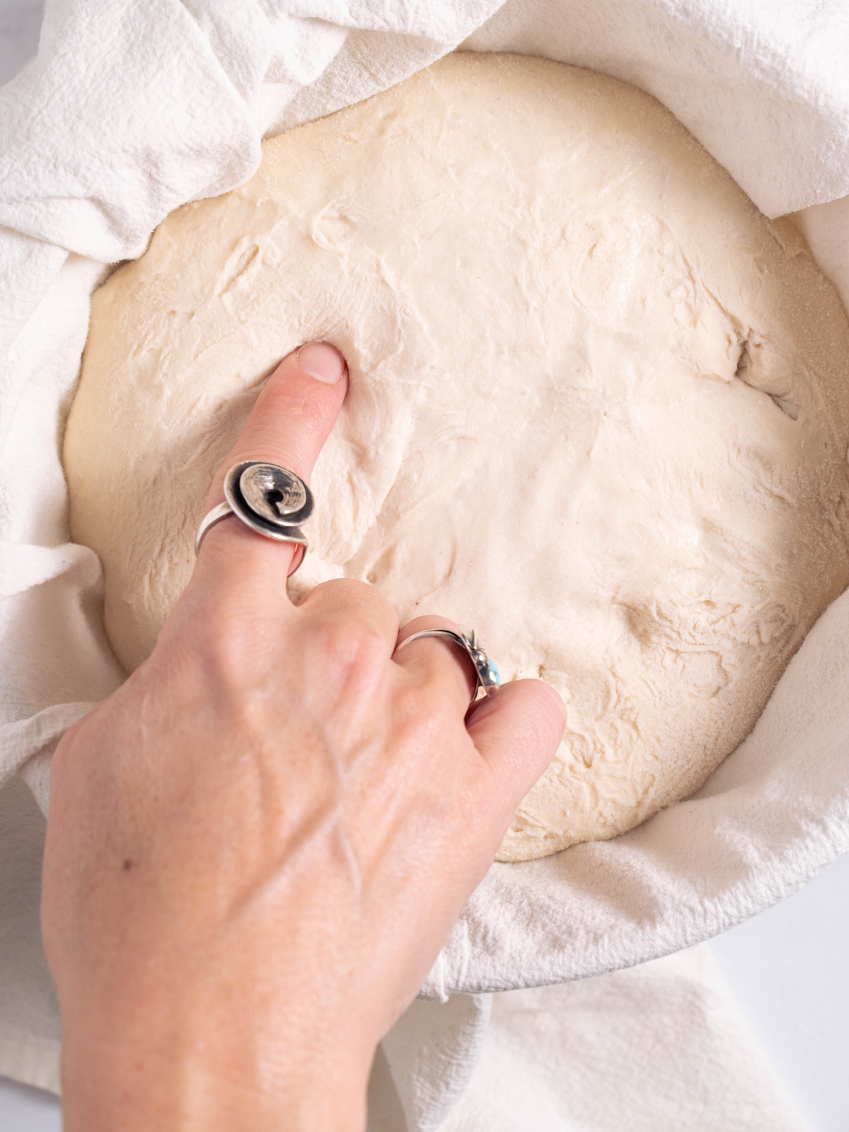 Pressing a finger into bread dough to see if it's properly proofed