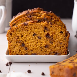 A loaf of sourdough pumpkin bread, sliced on a white platter