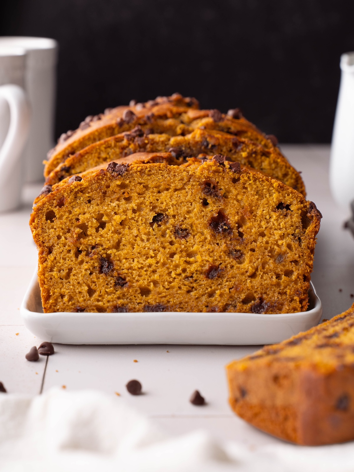 A loaf of sourdough pumpkin bread, sliced on a white platter